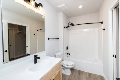 A white bathroom with a toilet, sink, and mirror.