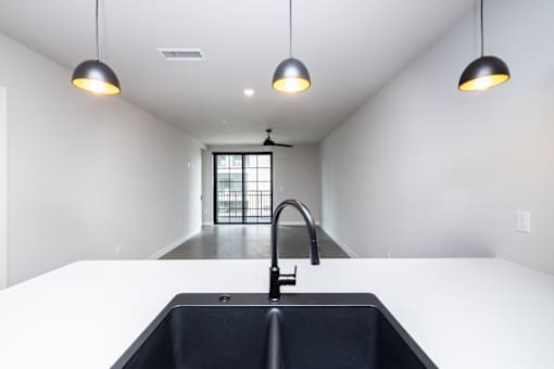 A modern kitchen with a black sink and pendant lights.