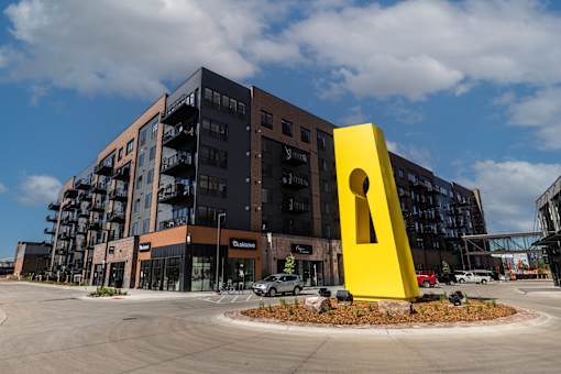 A large yellow keyhole sculpture is in front of a multi-story building.
