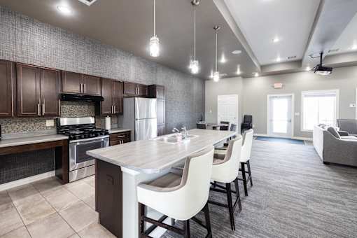 A modern kitchen with a large island and white chairs.