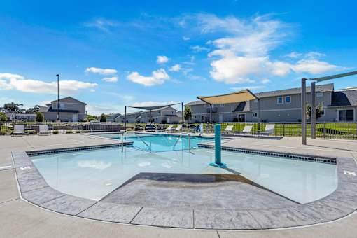 A large outdoor swimming pool with a diving board and lounge chairs.
