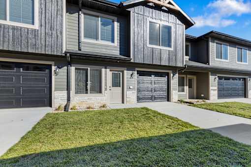 A row of houses with garages and front yards.