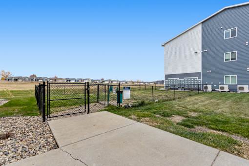 A fenced area with a sign and a building in the background.