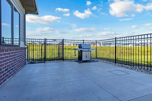 A black metal fence surrounds a concrete patio with a trash can in the middle.