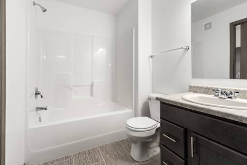 A white toilet sits next to a white bathtub in a bathroom.