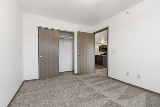 A room with a carpeted floor and two doors.