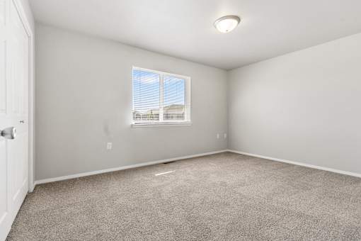 A room with a carpeted floor and a window.