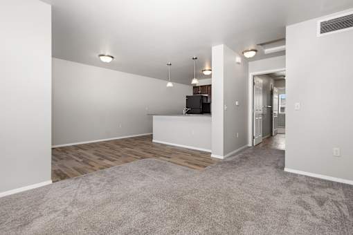 A spacious living room with a grey carpet and white walls.