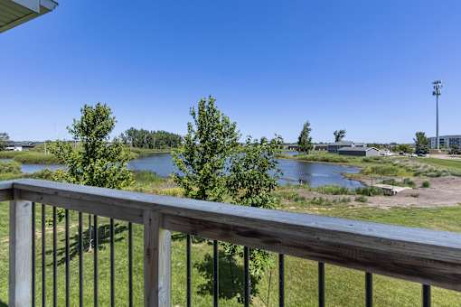 A balcony overlooks a river and a field.