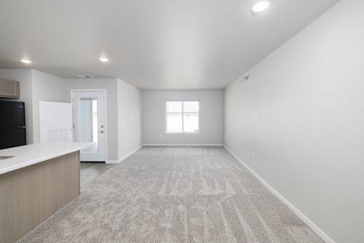 A spacious, empty room with a carpeted floor and a window.