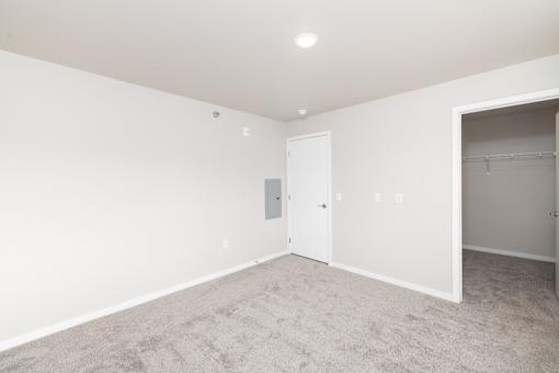 A room with a carpeted floor and a door on the left side.
