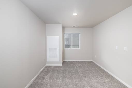 A room with a carpeted floor and a window with a balcony.