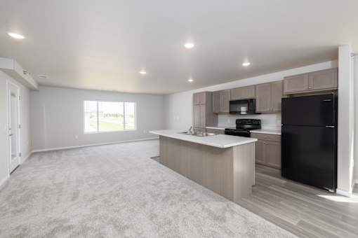 A spacious kitchen with a black refrigerator and a microwave above the counter.