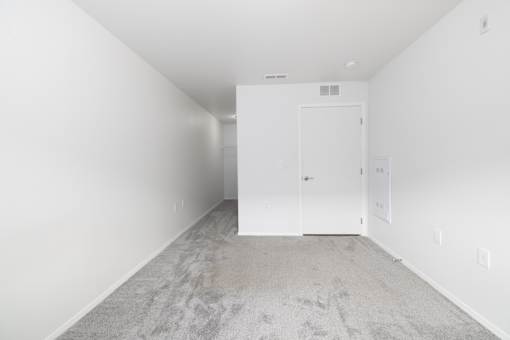 A room with a carpeted floor and a white door.