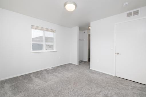 A room with a carpeted floor and a window.
