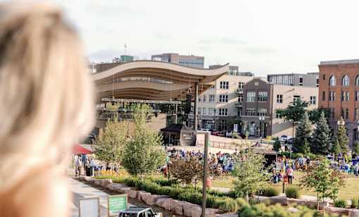 A woman with blonde hair is looking at a park with people walking around.