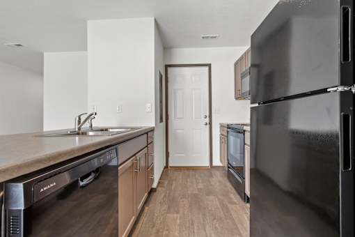 A kitchen with a black refrigerator and wooden cabinets.