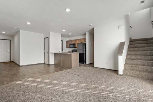 A spacious living room with a staircase on the right side.