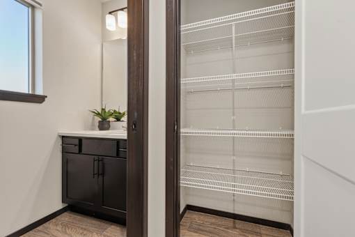 A potted plant sits on a countertop next to a window in a kitchen with a black fridge and wooden floors.