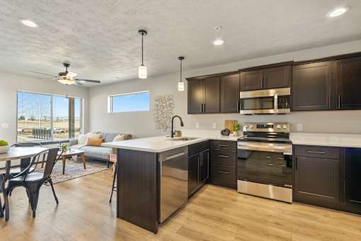 A modern kitchen with dark brown cabinets and stainless steel appliances.
