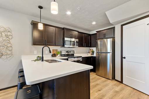 A modern kitchen with dark brown cabinets and a white countertop.