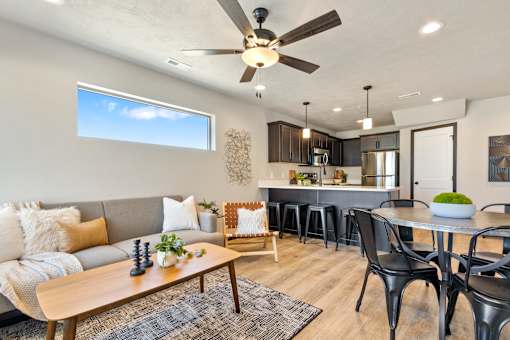 A modern living room with a grey sofa, a wooden coffee table, and a ceiling fan.
