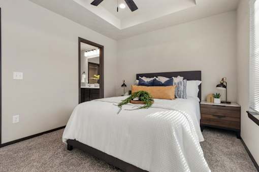 A bedroom with a bed, pillows, and a plant on the bed.