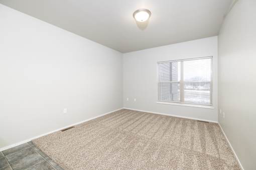 A room with a carpeted floor and a window.