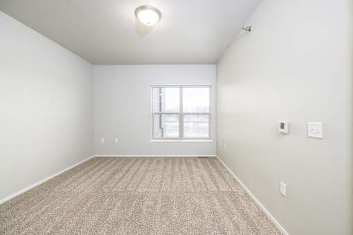 A room with a carpeted floor and a window.