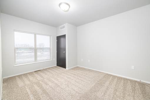 A room with a carpeted floor and a door.
