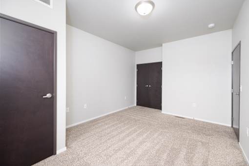 A room with a carpeted floor and two doors.