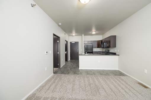 A spacious living room with a kitchen area in the background.
