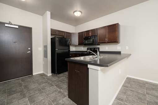 A kitchen with black appliances and brown cabinets.