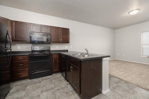 A kitchen with brown cabinets and a black refrigerator.
