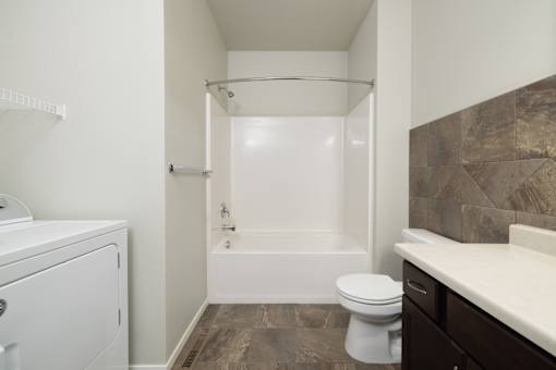 A white toilet sits next to a bathtub in a bathroom.
