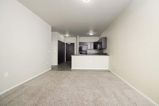 A spacious room with a kitchen area in the background.