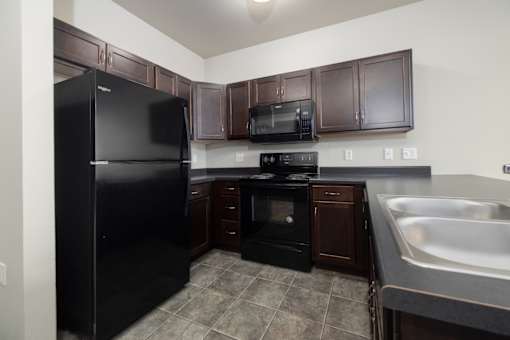 A kitchen with black appliances and brown cabinets.