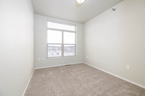 A room with a carpeted floor and a window.