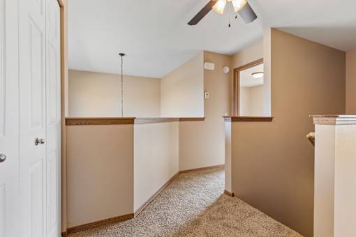 A room with a white door and a ceiling fan.