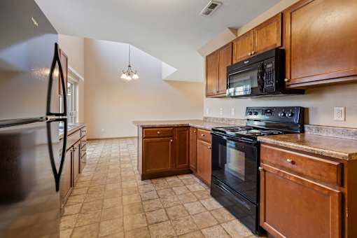 A kitchen with black appliances and wooden cabinets.