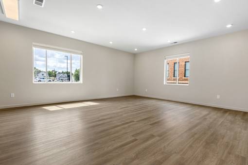 A large empty room with wooden flooring and a window.