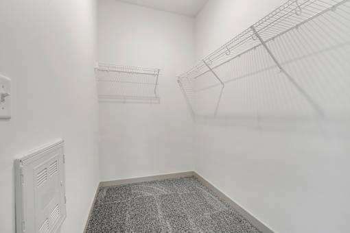 A white wall with a wire shelf and a vent.
