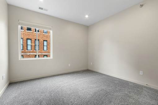 A room with a large window and a view of a brick building outside.