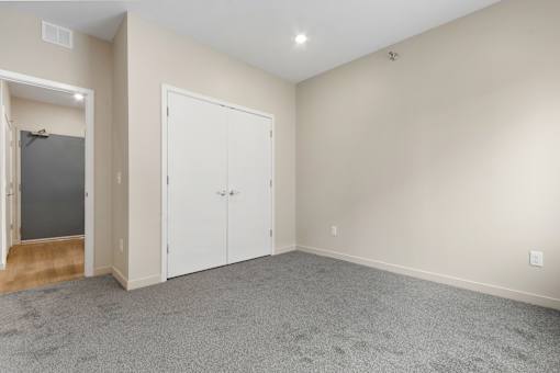 A room with a carpeted floor and two white doors.
