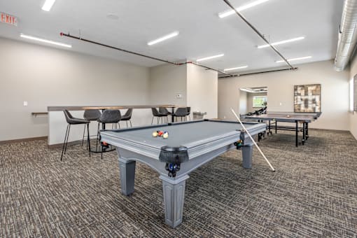 A pool table in a room with a carpeted floor and a white ceiling.
