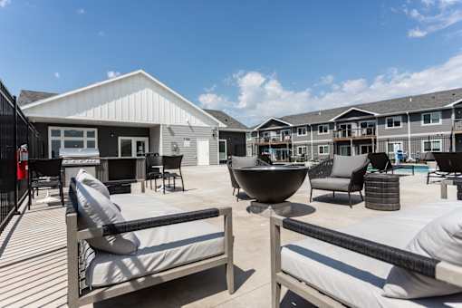 A sunny day at a modern outdoor living space with a fire pit and seating area.