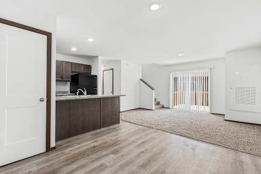 A modern kitchen with a white door and wooden flooring.