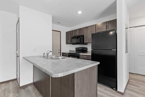 A kitchen with a black fridge and microwave.