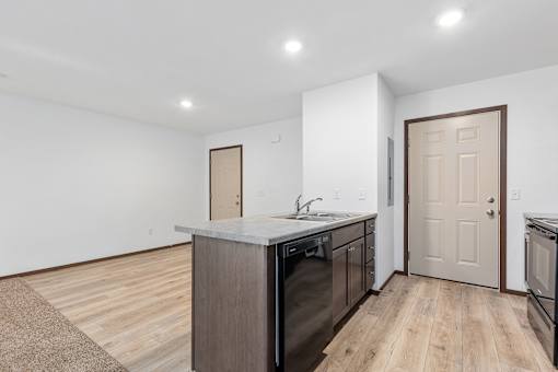 A kitchen with a white countertop and wooden floors.