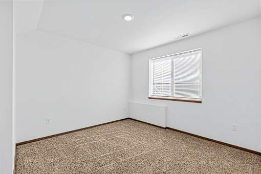 A room with a window and carpeted floor.